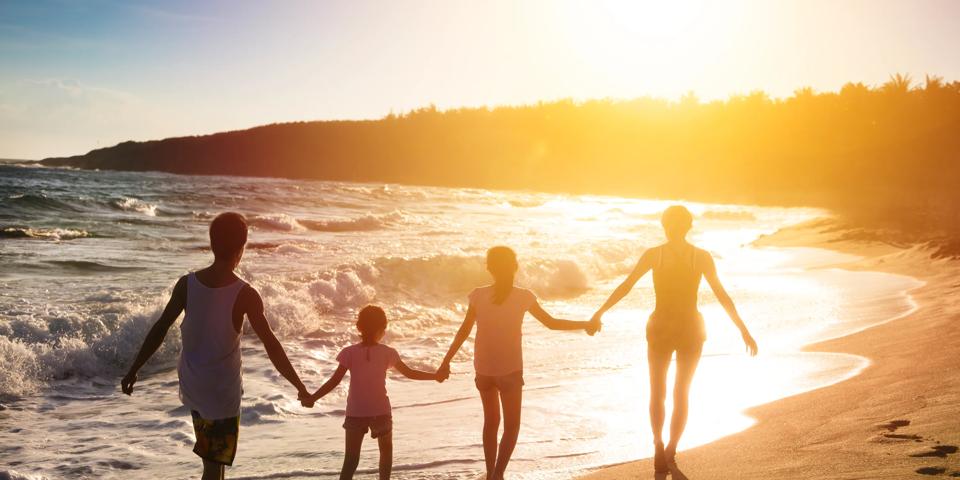 family holding hands from behind on the beach